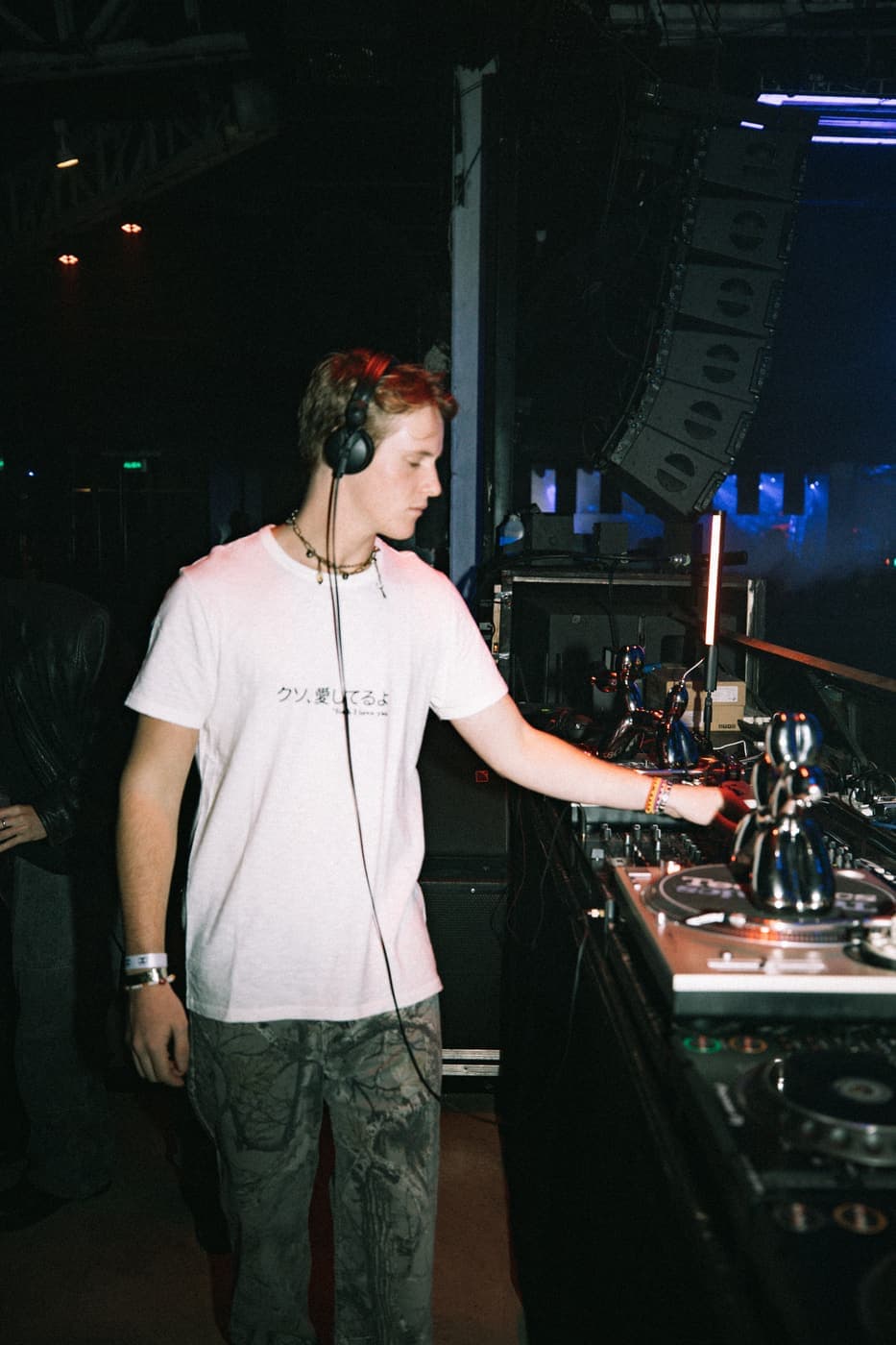 Un DJ de perfil sobre los platos, con los auriculares puestos, en The Bow