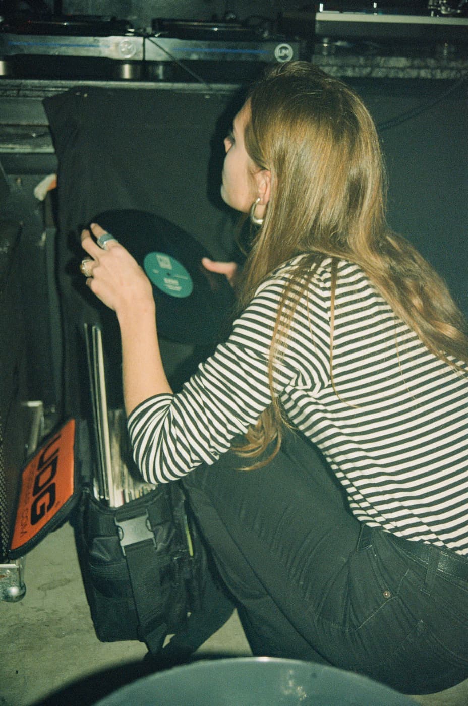Alguien agachada junto al cajón, sacando un disco, en The Bow