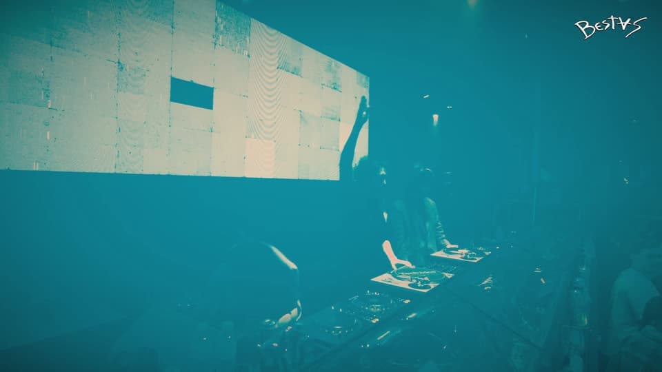 Un DJ bajo la proyección celeste, con la pared encendida, en The Bow