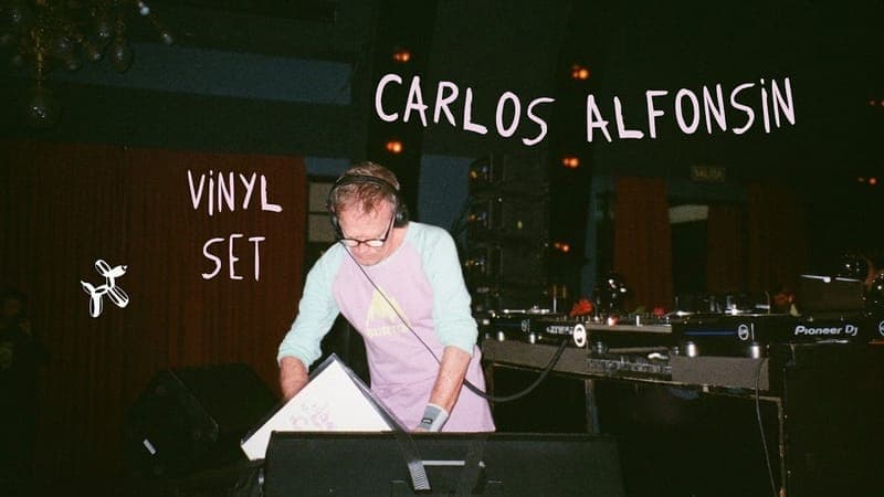 Carlos Alfonsin pasando vinilos en la cabina, con «Carlos Alfonsin vinyl set» escrito a mano.