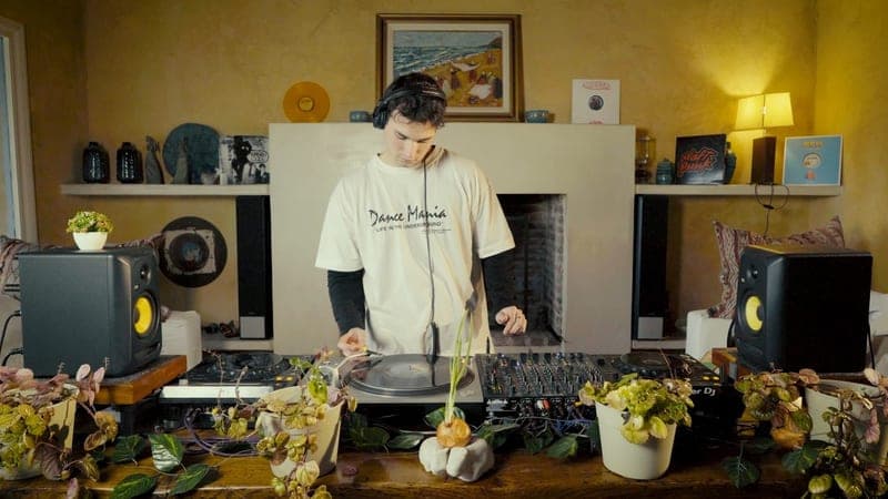Manu Alcacer en el living de su casa, con auriculares, pasando música entre plantas y parlantes.